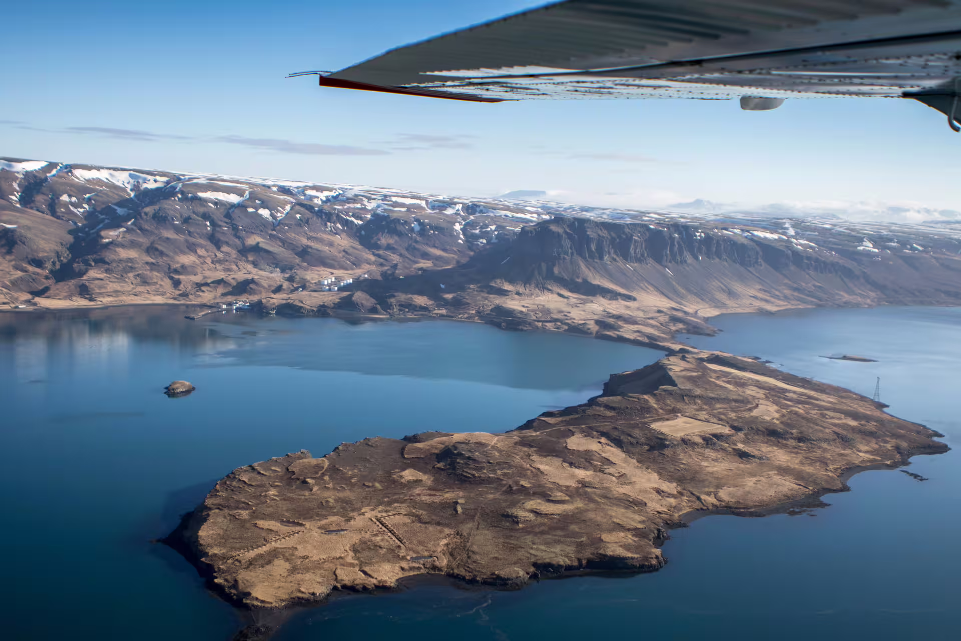 Aerial view of Icelandic fjord island with snow-capped mountains from small airplane window