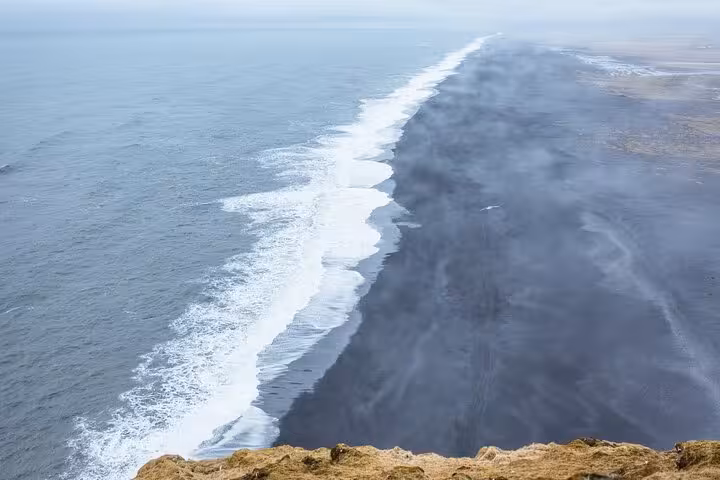 Aerial view of Iceland's black sand beach with white waves along the South Coast