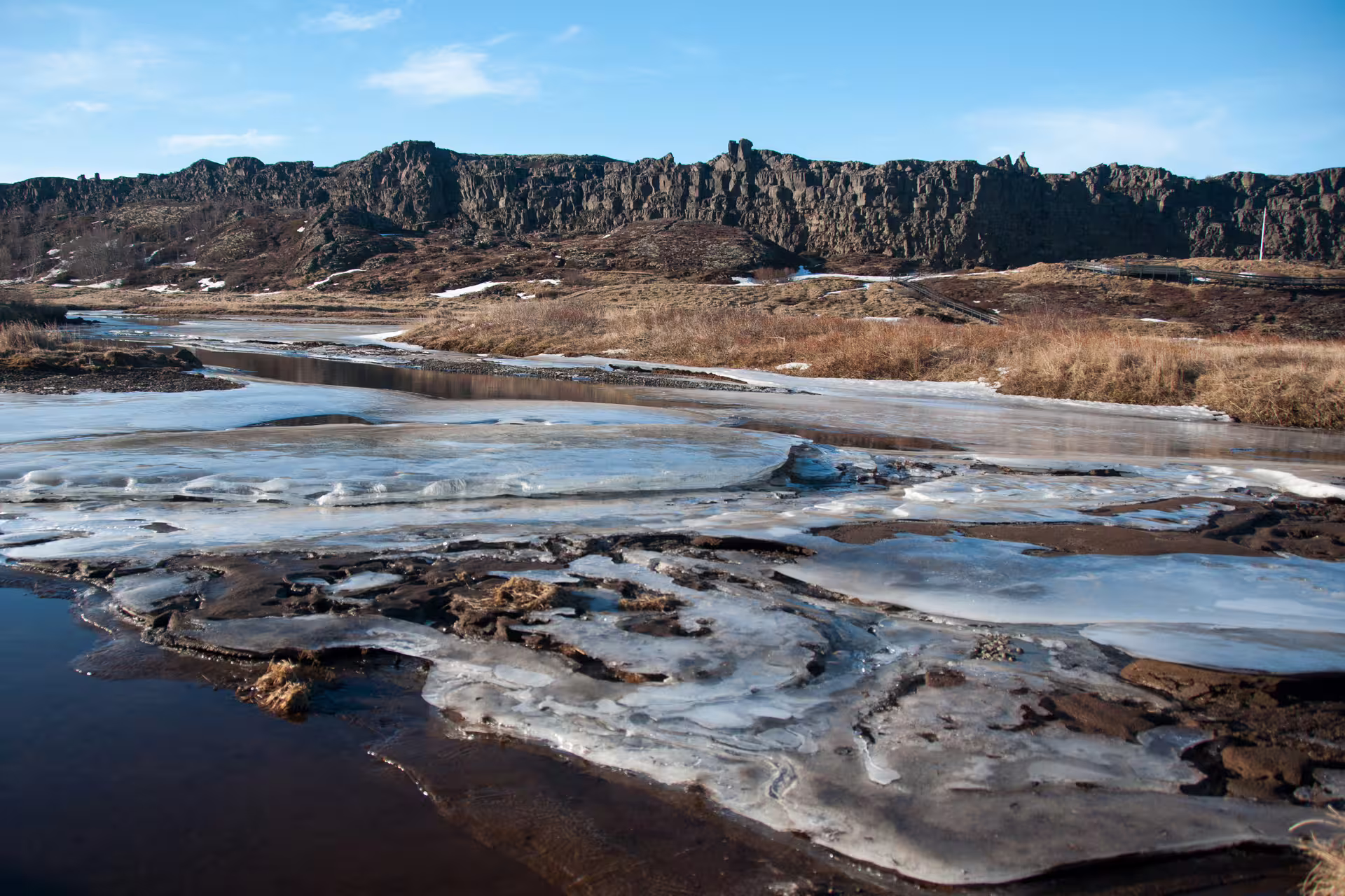 Icy river and jagged lava rock cliffs at Þingvellir National Park, Iceland in winter