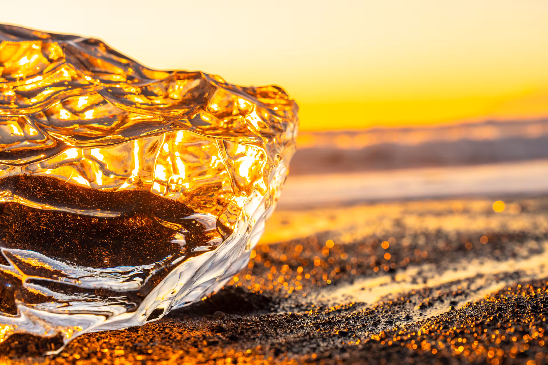 Glacial ice chunk glowing golden on Iceland's black sand Diamond Beach at sunset