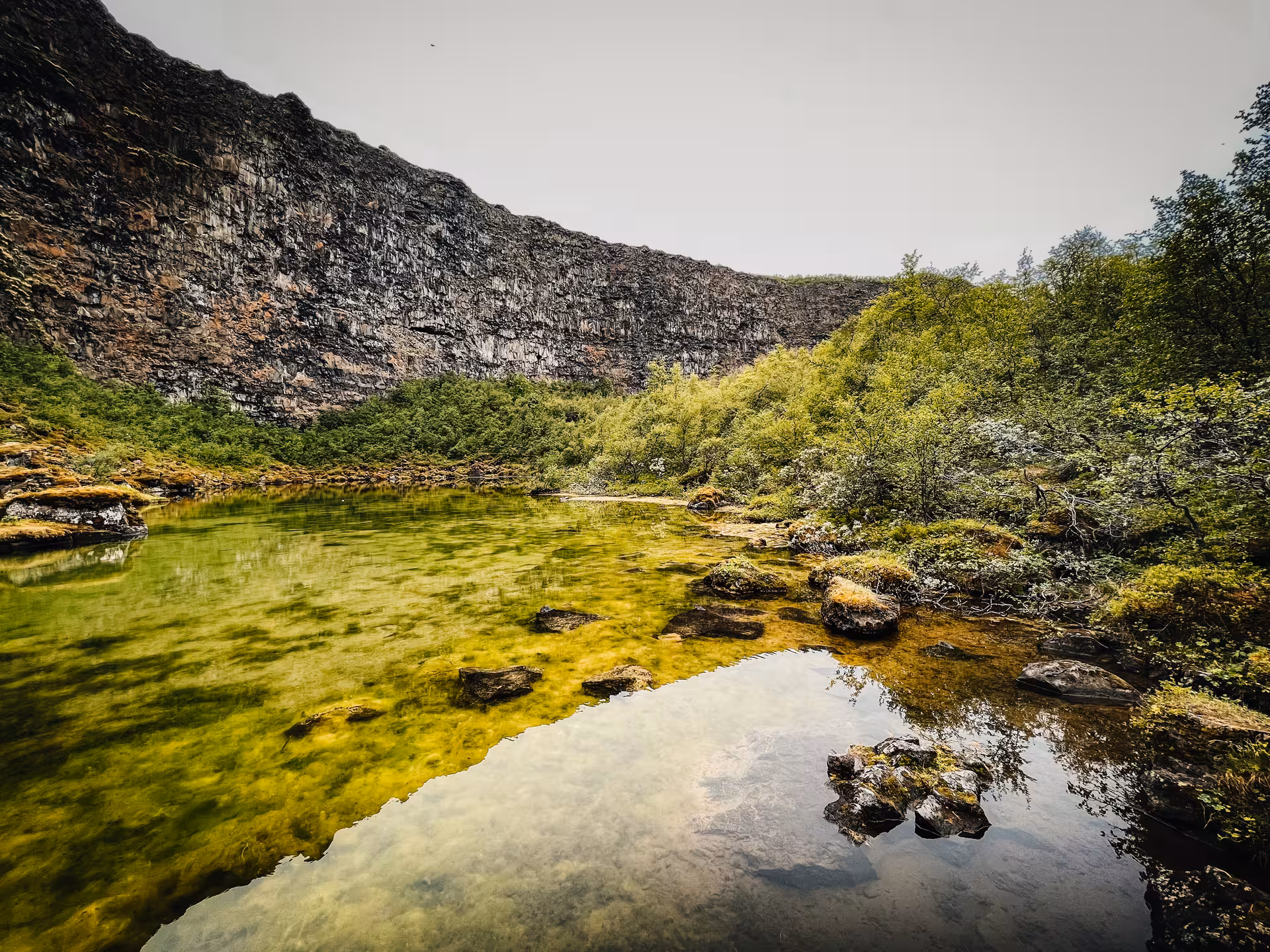 Green geothermal pond and lava cliffs at Lake Mývatn area, scenic stop on Iceland Adventure Diamond Circle Tour