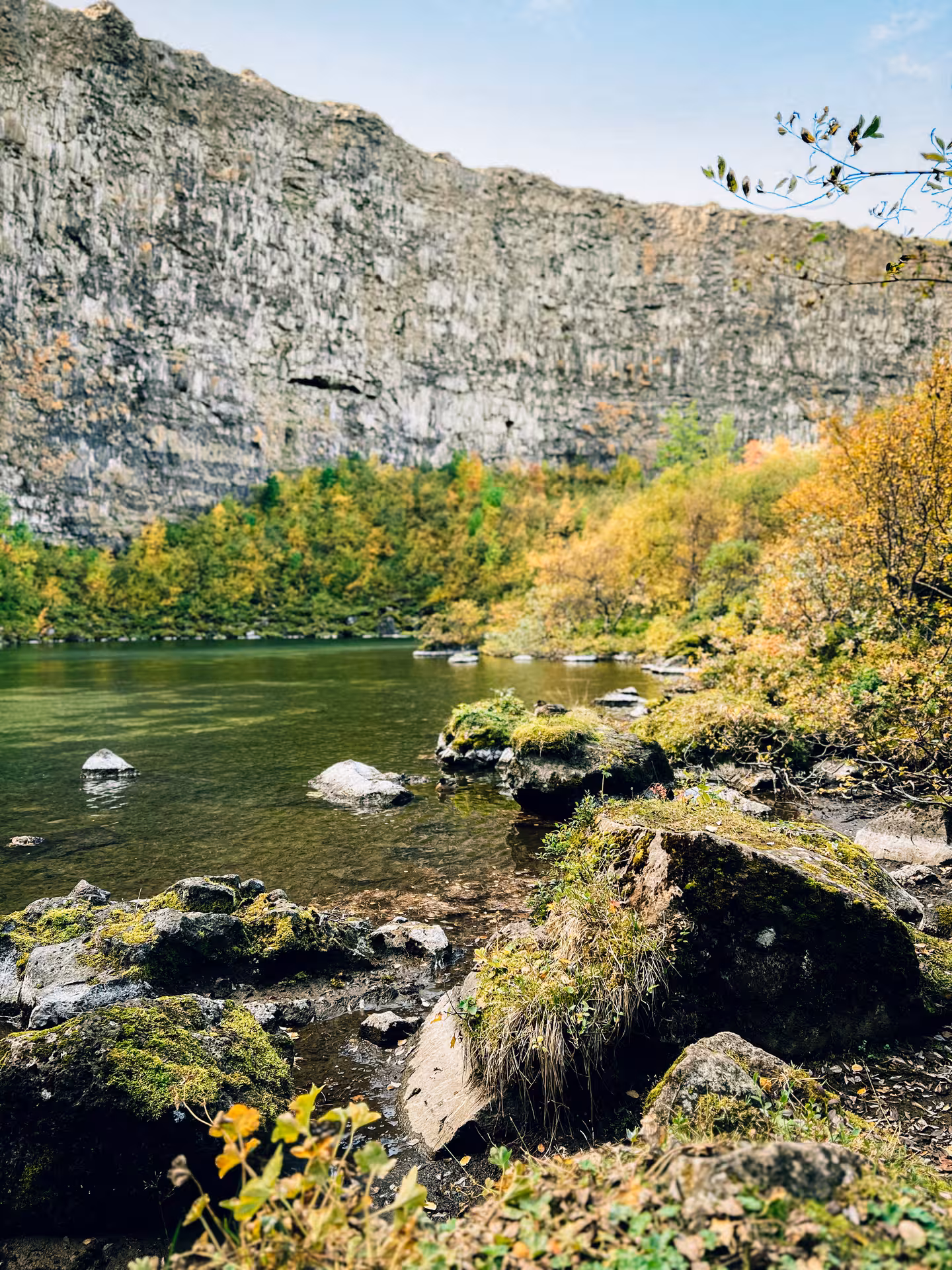 Tranquil lake and rocky shoreline beneath steep cliffs, a scenic stop on Iceland’s Diamond Circle Tour