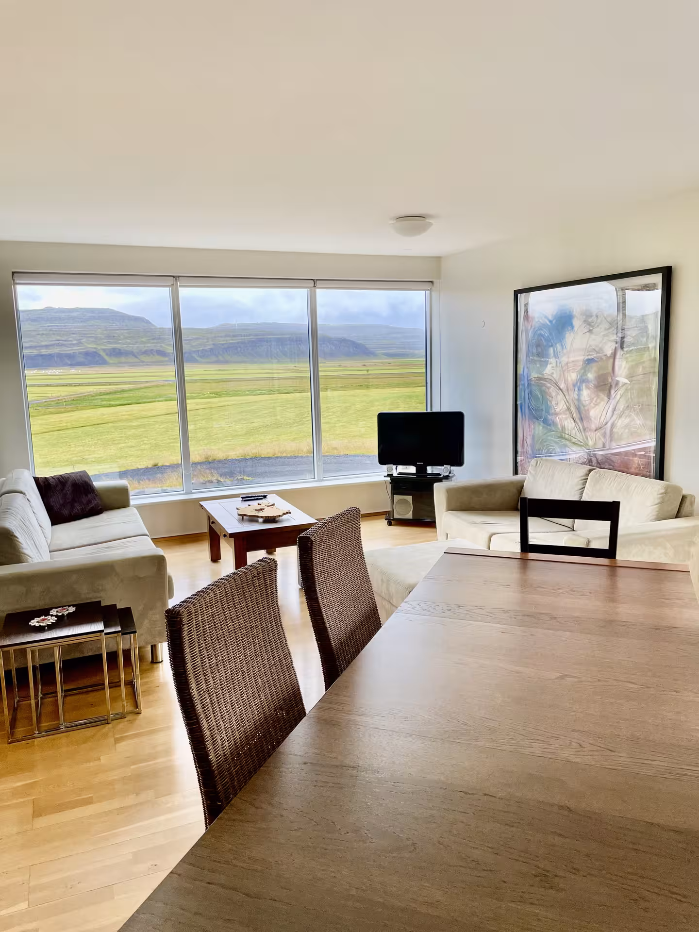 Bright Iceland farm stay living room with panoramic views of green fields and volcanic mountains