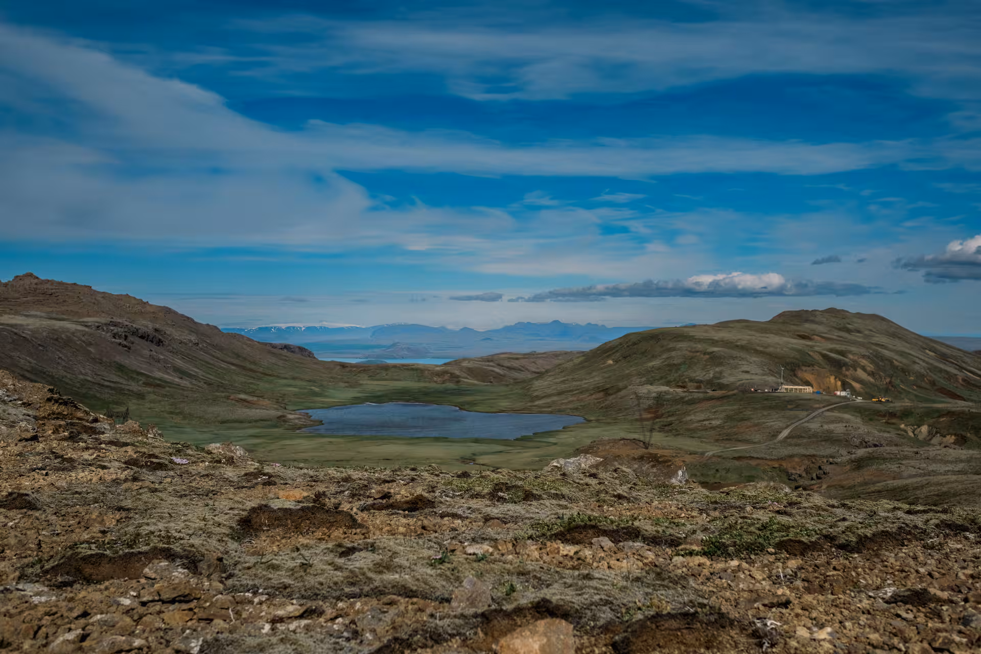 Geothermal valley with small lake surrounded by volcanic hills near Hengill Volcano, Iceland