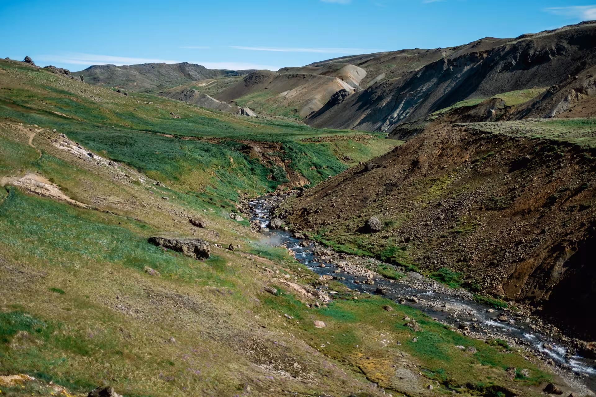 Rocky stream flowing through green geothermal valley near Hengill Volcano, Iceland
