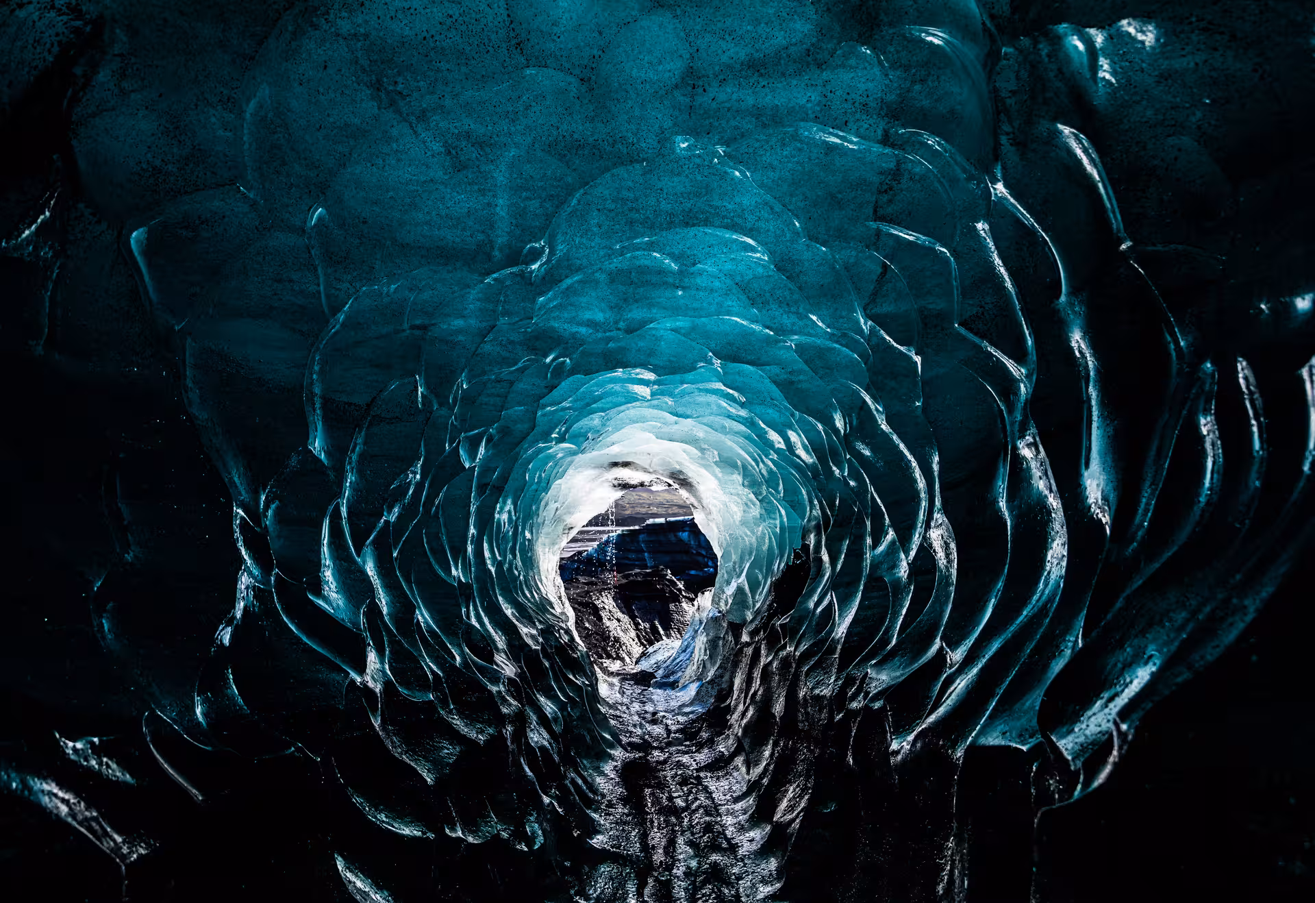 Glowing turquoise ice cave tunnel with layered glacial walls in Iceland