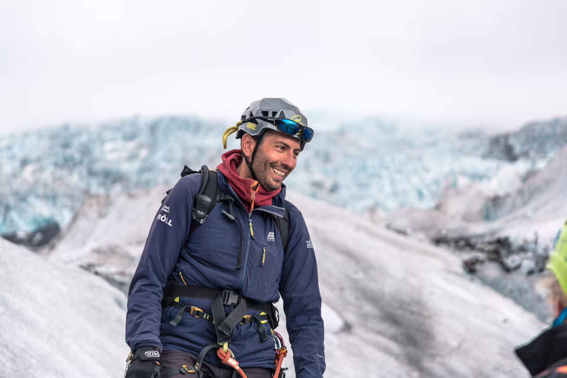 Smiling glacier guide in helmet and harness standing on Iceland glacier ice field