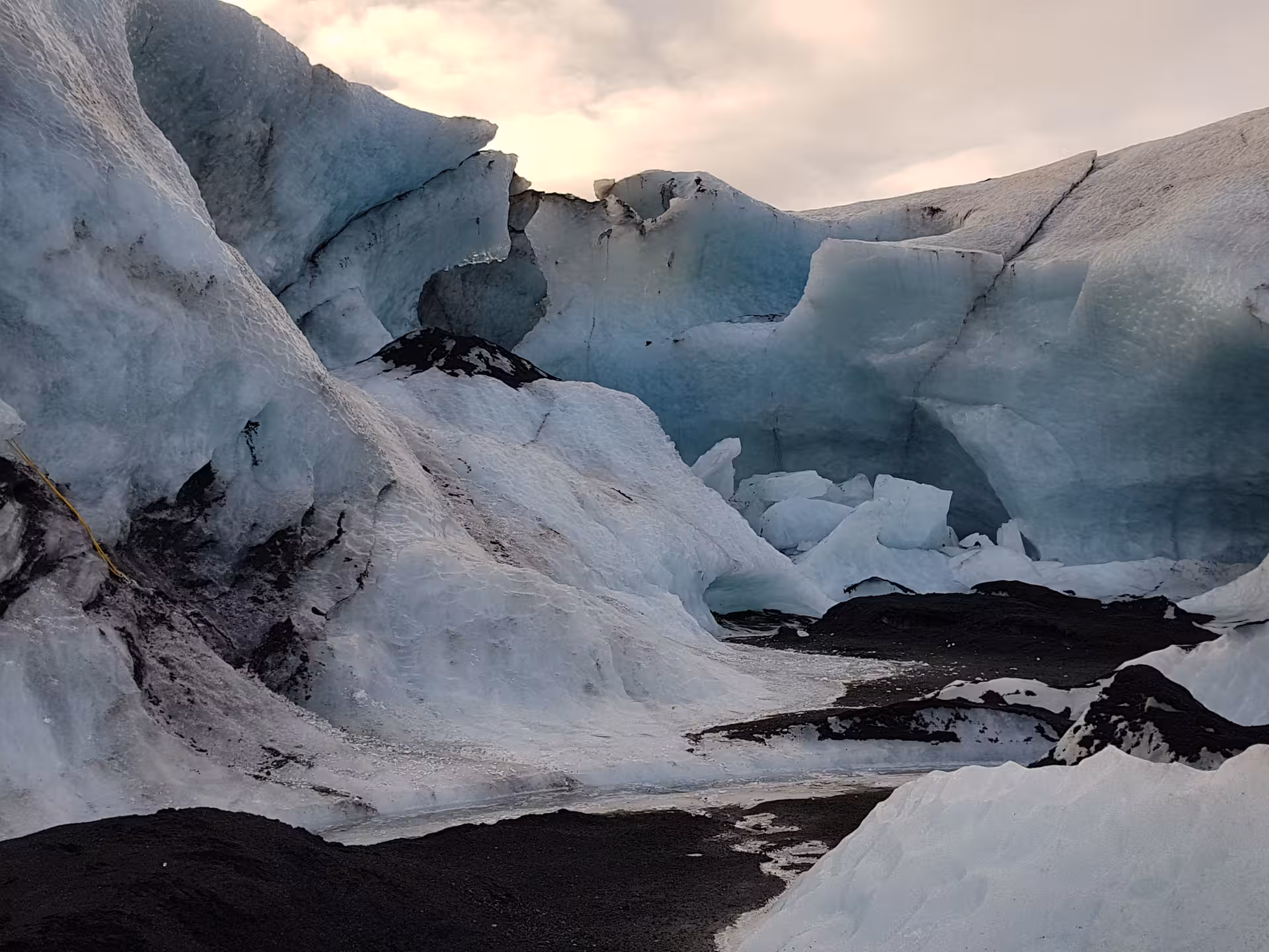 Blue glacial ice formations with dark volcanic rock at an Iceland glacier hike and ice climbing site