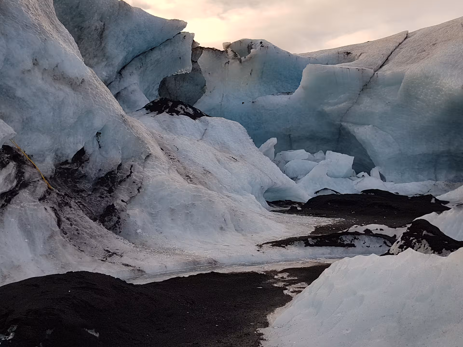 Blue glacial ice formations with black volcanic rock at an Iceland glacier hiking site