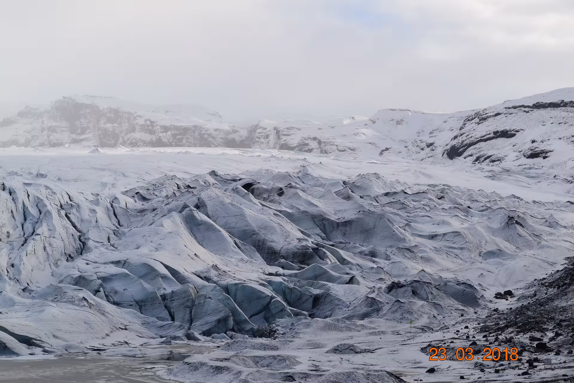 Rugged glacier ice formations with dark crevasses and snow-dusted ridges in Iceland on a cloudy winter day