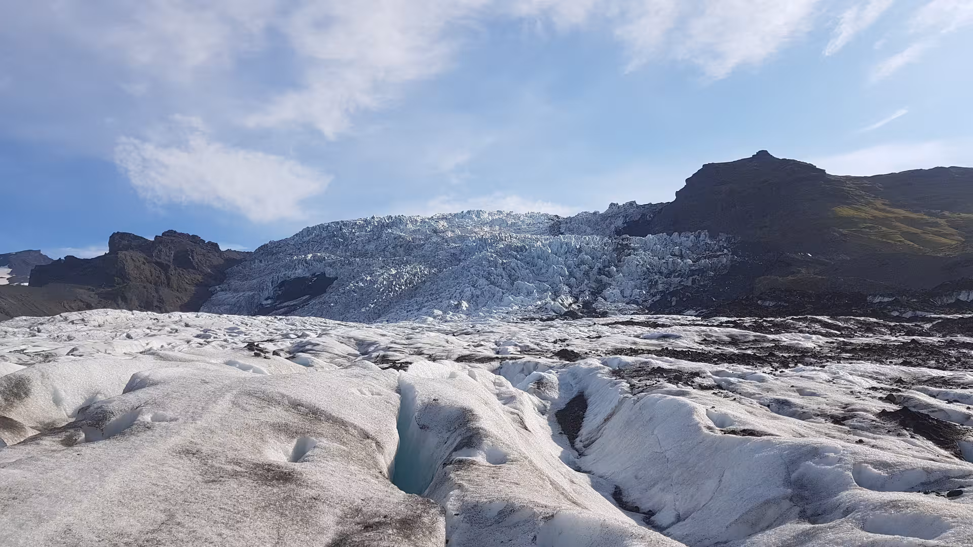 Vast glacier surface with deep ice crevasses and jagged ice wall in Icelandic highland landscape