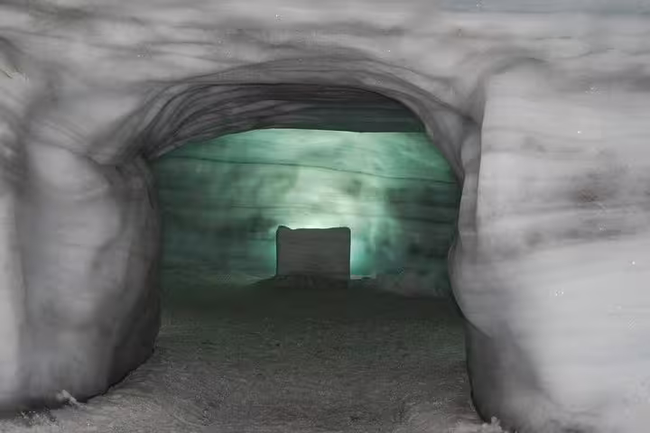 Glowing ice tunnel passage inside an Icelandic glacier with green-lit interior