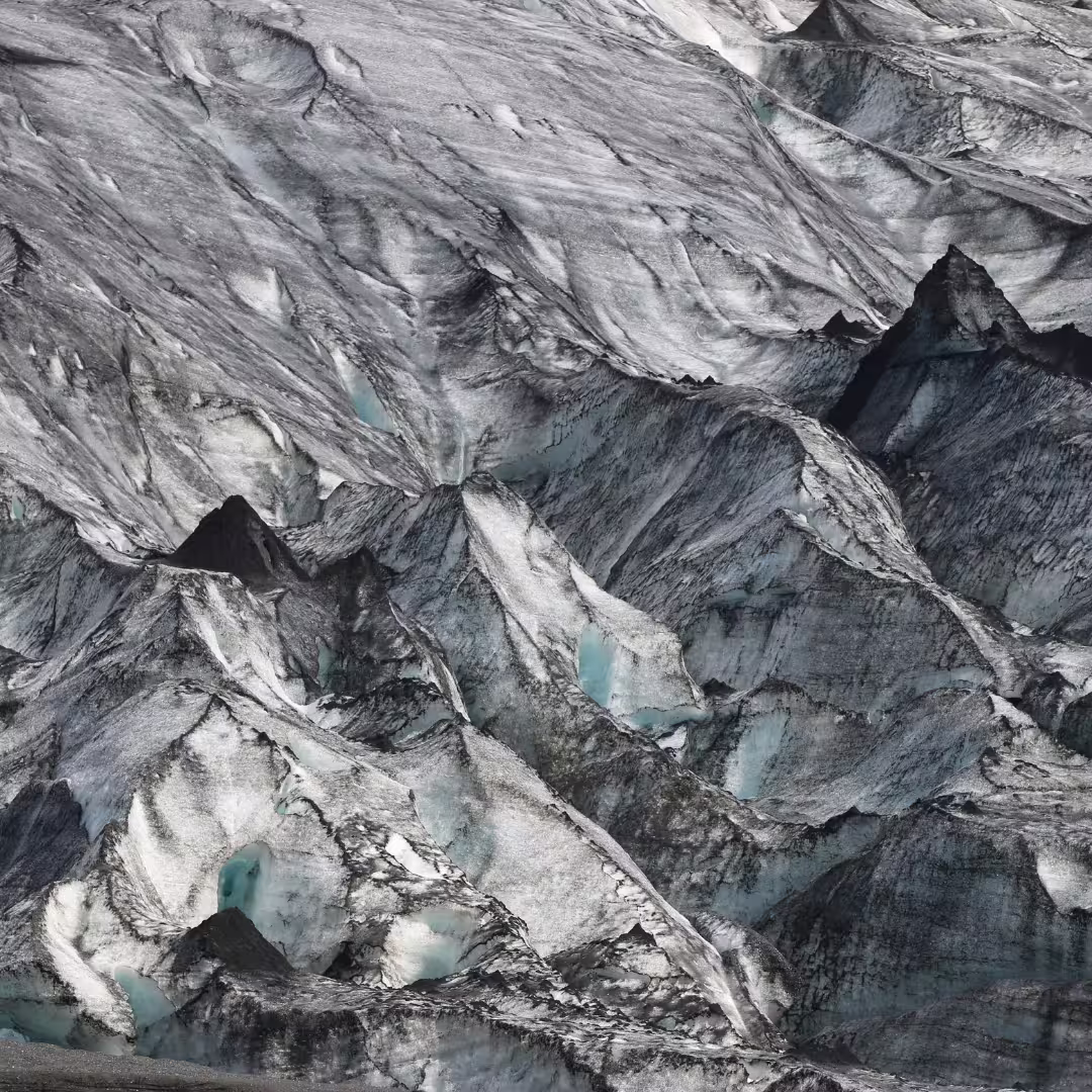 Close-up of rugged Iceland glacier ice formations with dark volcanic ash streaks on a South Coast day trip from Reykjavik.