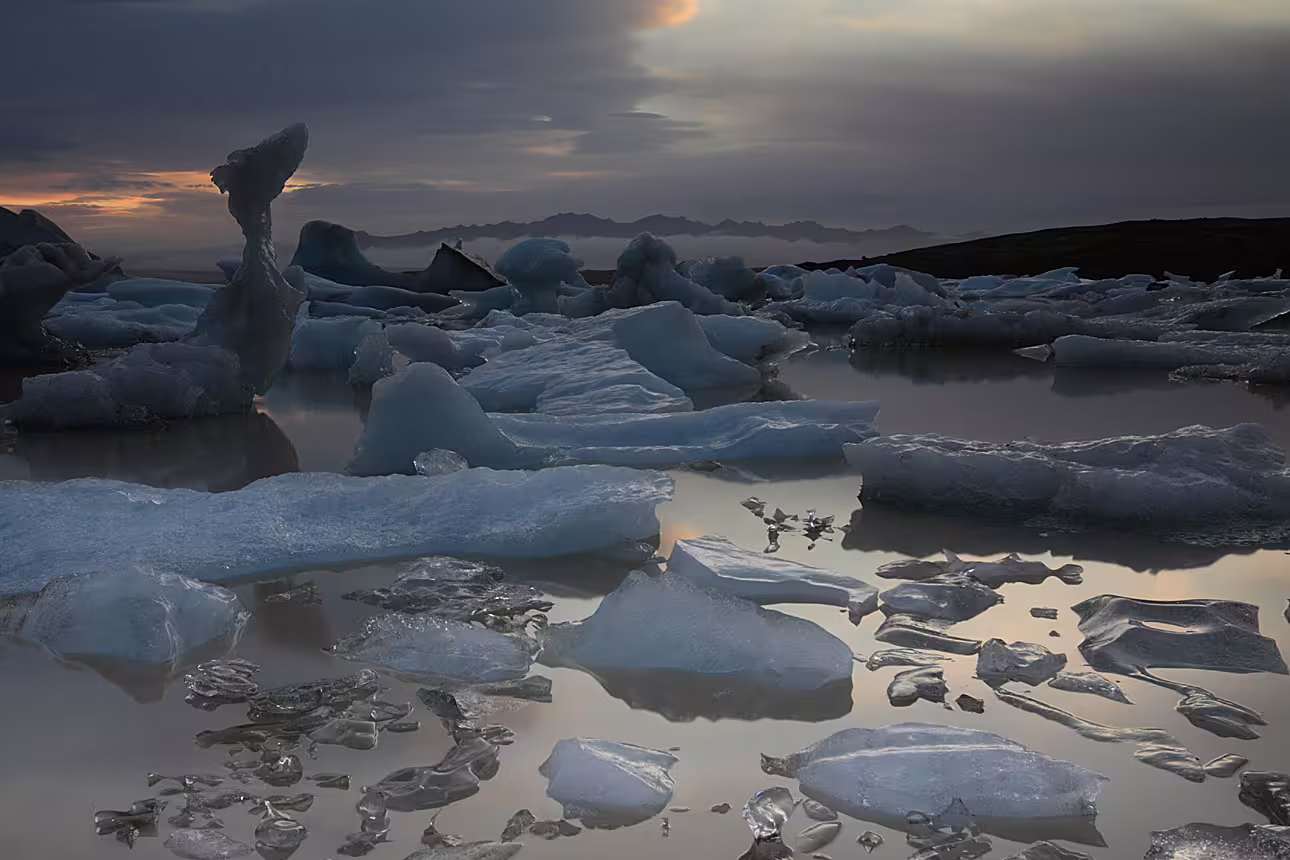 Ice chunks floating on Jokulsarlon Glacier Lagoon at dusk with dramatic cloudy sky in Iceland