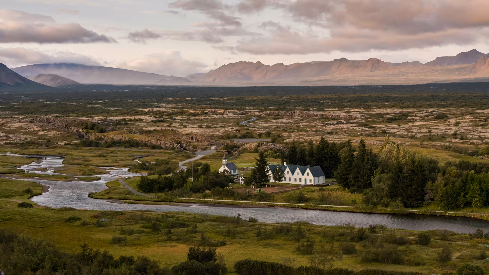 Scenic view of Icelandic landscape with a river, lush greenery, and distant mountains on the Golden Circle tour.