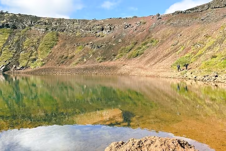 Volcanic crater lake with green reflections and rocky slopes on Iceland's Golden Circle tour