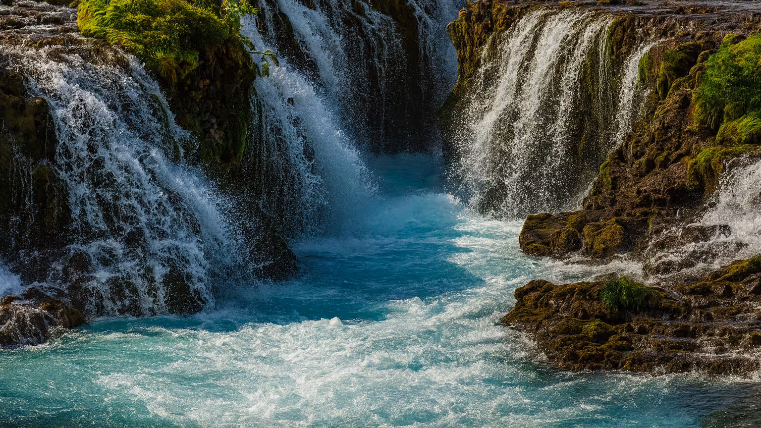 Vibrant waterfall cascades over moss-covered rocks in Iceland's Golden Circle, showcasing natural beauty.