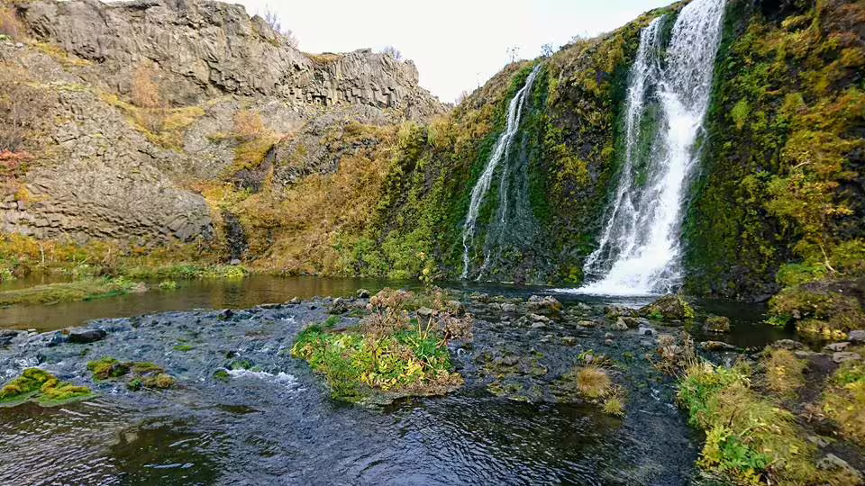 Secluded Iceland waterfall flowing into calm pool surrounded by basalt cliffs on a private Super Jeep tour