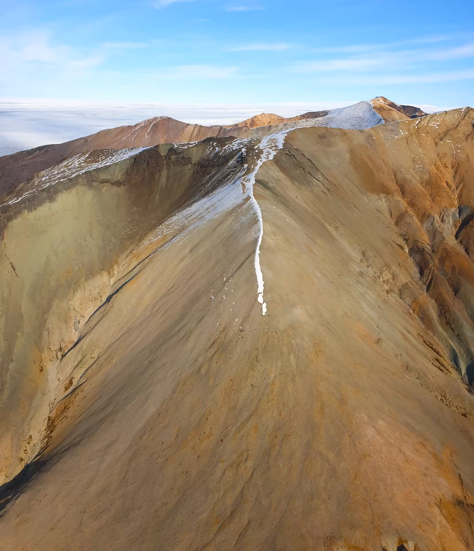 Aerial view of colorful rhyolite mountain ridge with snow streak in Iceland's highland landscape