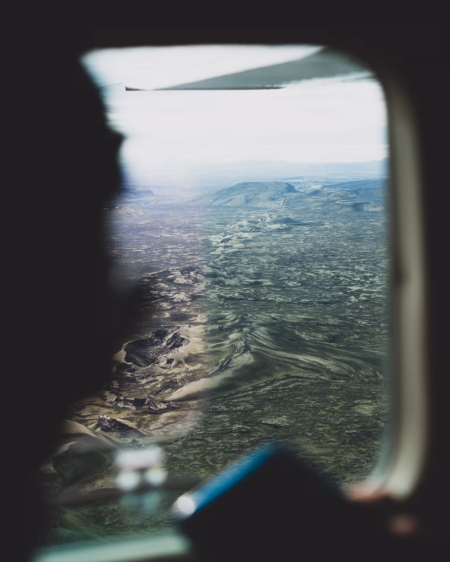 Aerial view of Iceland highlands volcanic landscape and green terrain seen through small plane window