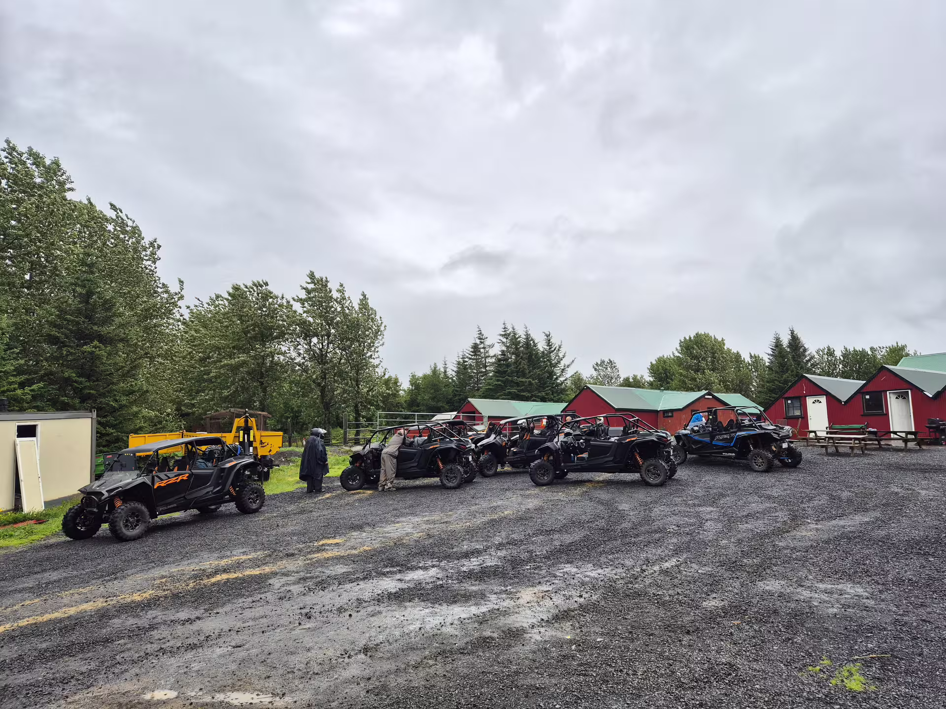 Fleet of black Polaris RZR buggies lined up on gravel near red cabins in Iceland highlands