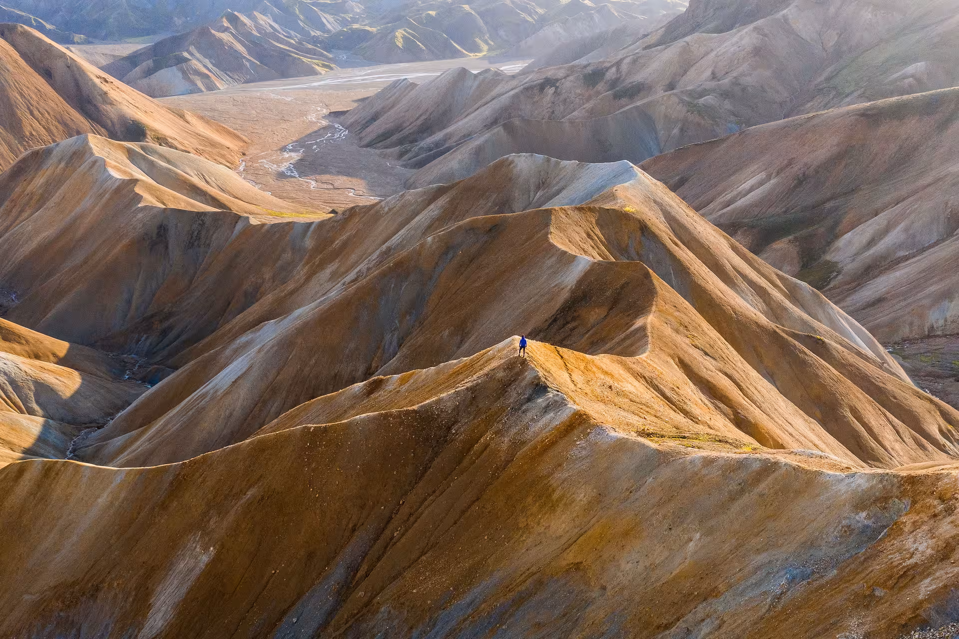 Hiker standing on colorful rhyolite mountain ridge in Iceland's Highland wilderness