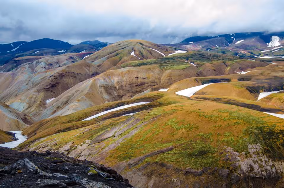 Colorful rhyolite mountains with snow patches in Iceland Highlands under dramatic cloudy sky