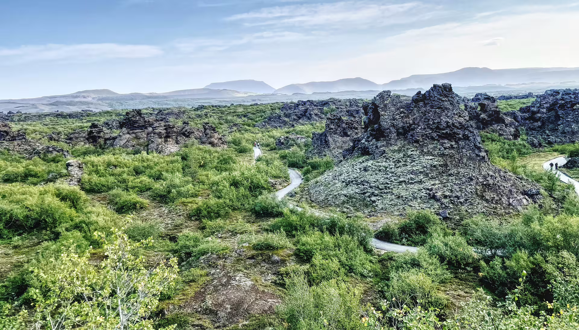 Winding highland trail through lush green lava fields with volcanic rock formations on Secrets of the Highlands 10-day tour