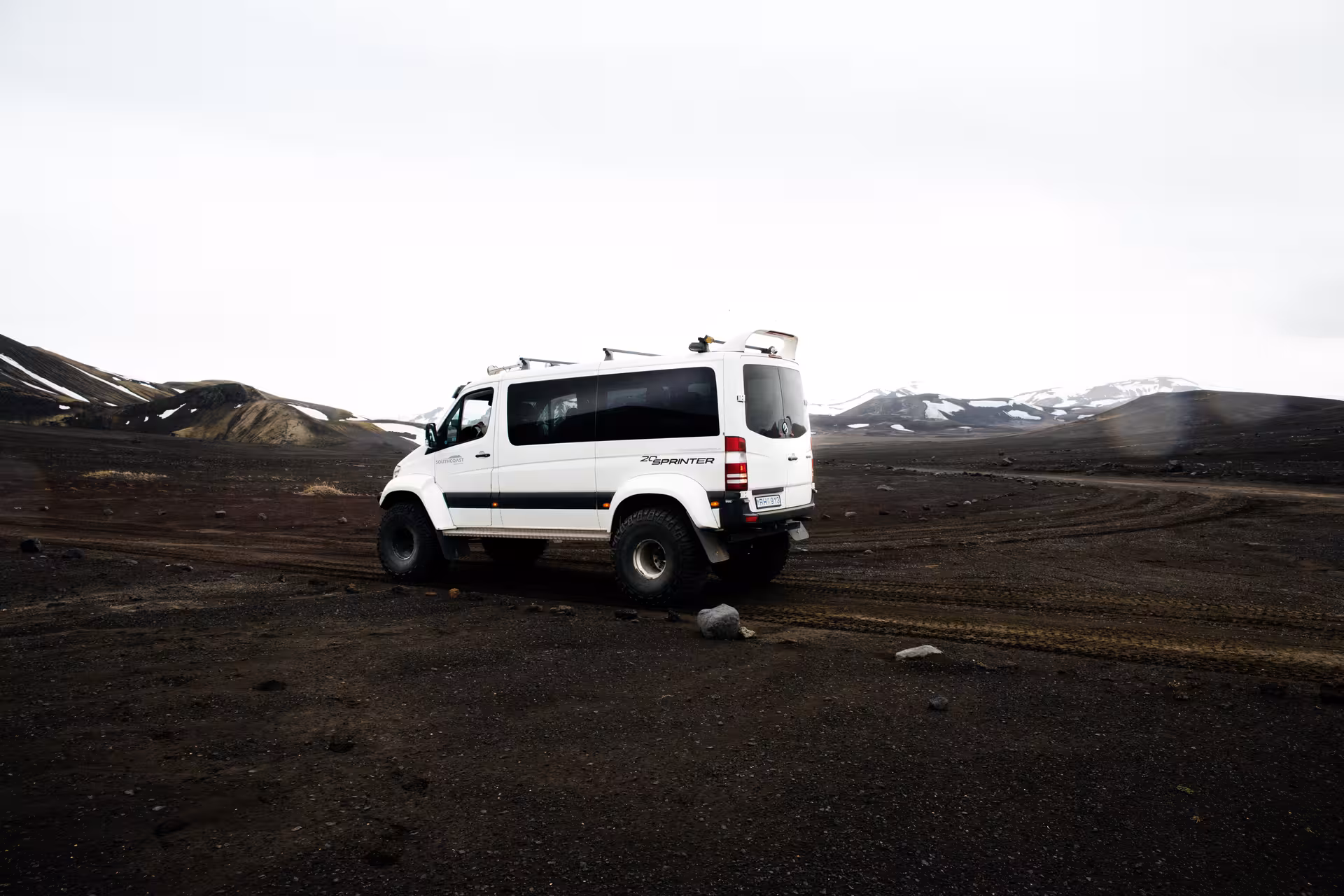 White lifted Mercedes Sprinter super jeep on black volcanic terrain in Iceland highlands