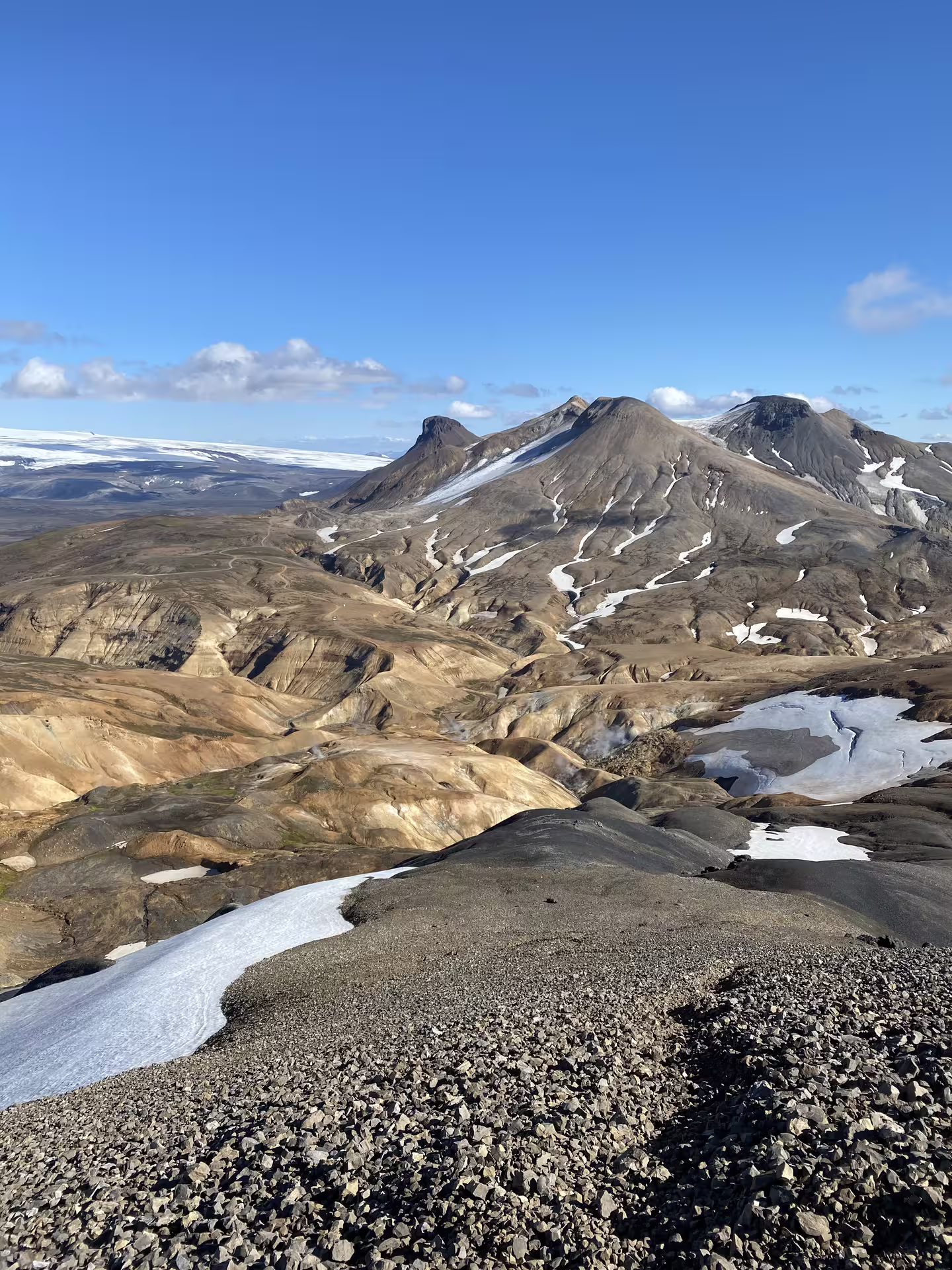 Dramatic Iceland highlands volcanic landscape with snow patches and rugged mountains under clear blue sky on a highlands adventure tour