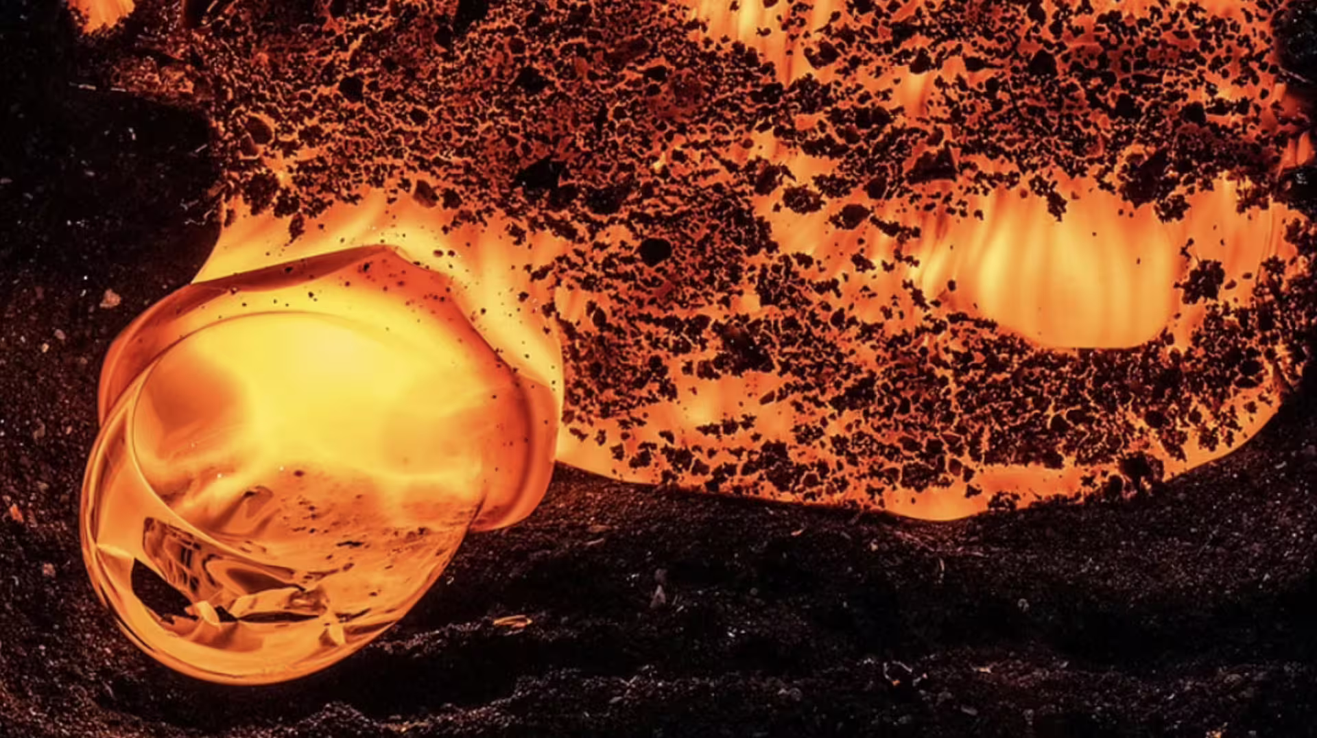 Glowing molten lava bubble forming on dark volcanic rock during Iceland lava show