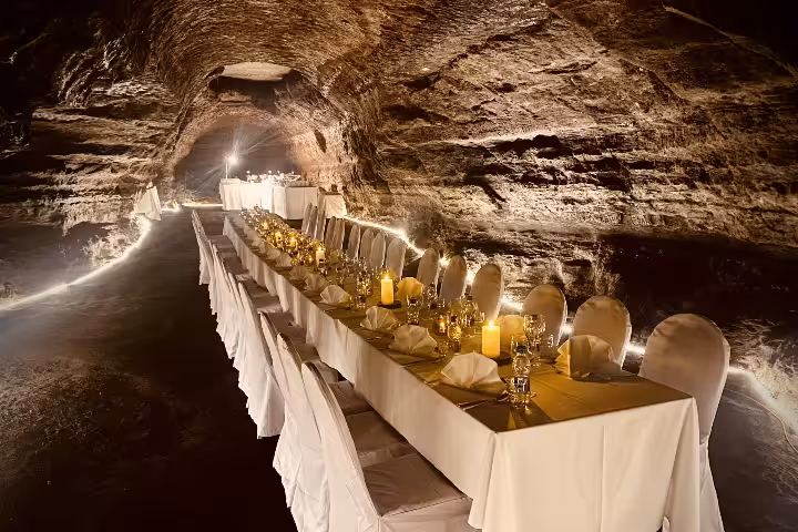 Arctic Table luxury cave dinner with white-draped chairs and glowing candles inside an Iceland lava tunnel