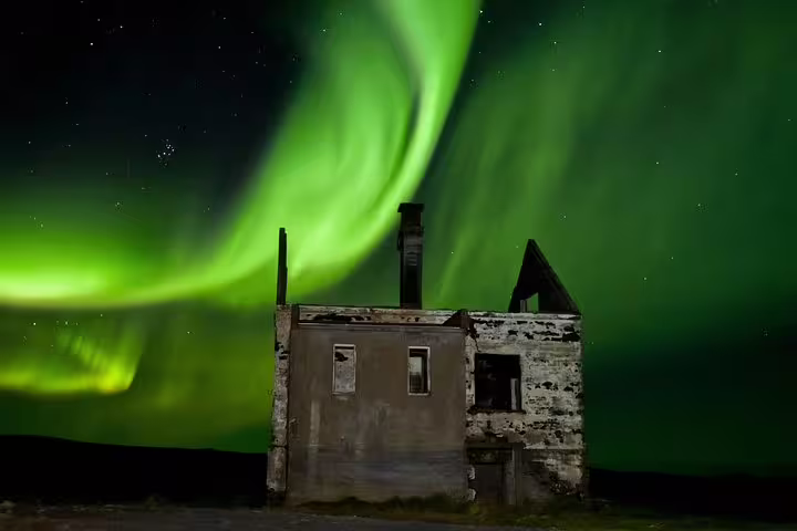 Northern lights aurora borealis swirling green over abandoned stone ruins in Iceland night sky
