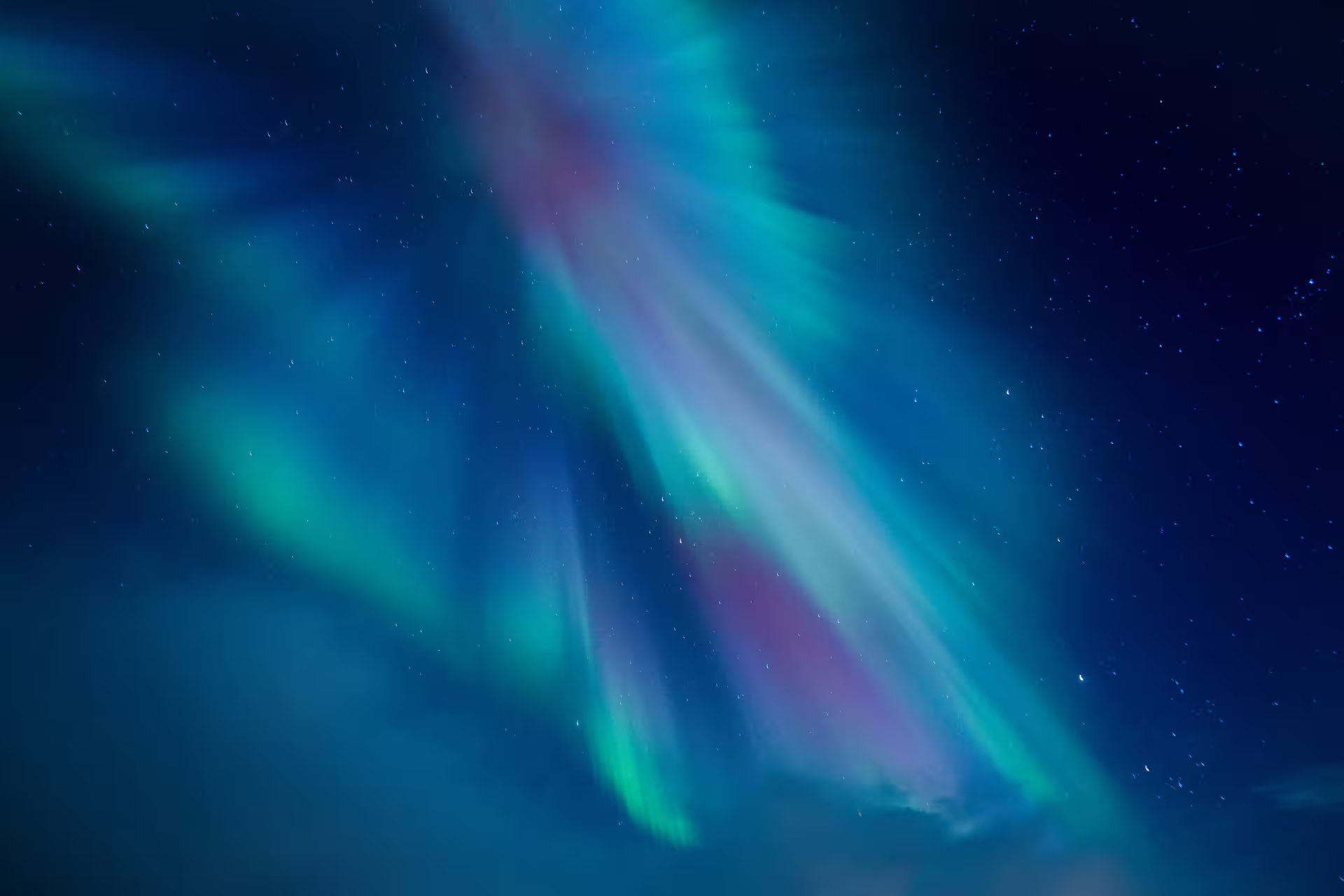 Vibrant aurora borealis with green, pink, and blue lights dancing across Iceland's starry night sky