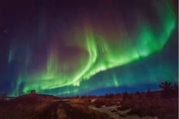 Vivid green and purple northern lights aurora borealis dancing over Iceland's dark landscape at night