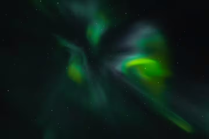 Vibrant green and yellow aurora borealis swirling across a dark starry night sky in Iceland