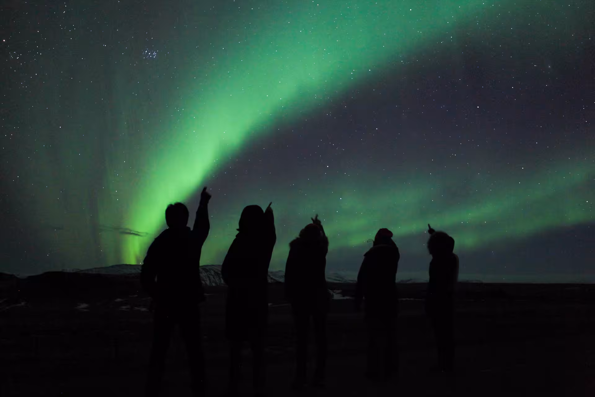 Group admiring Northern Lights under starry sky in Iceland on 6-Day Stopover Tour.