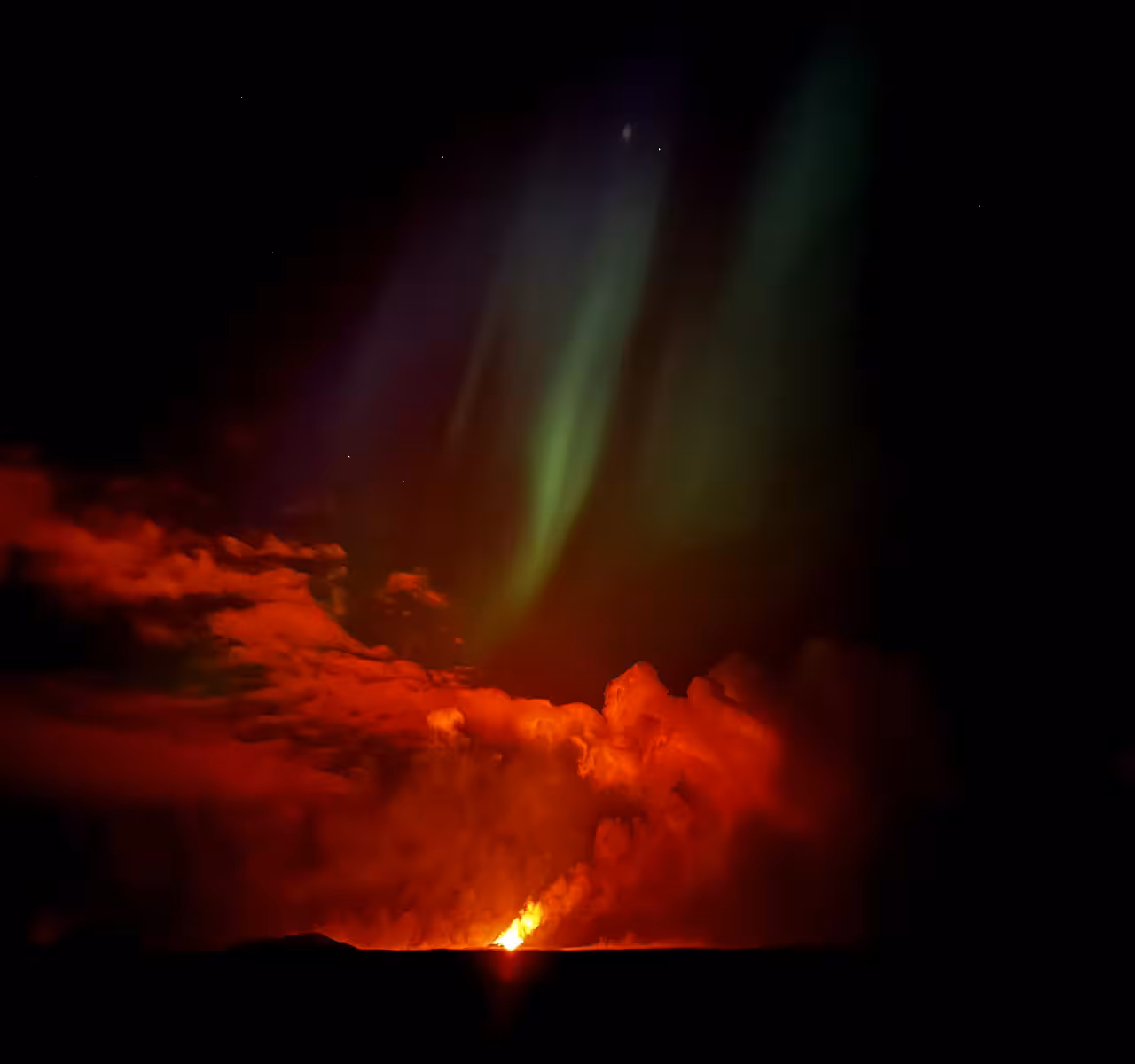 Volcanic eruption glowing red under green aurora borealis in Iceland night sky