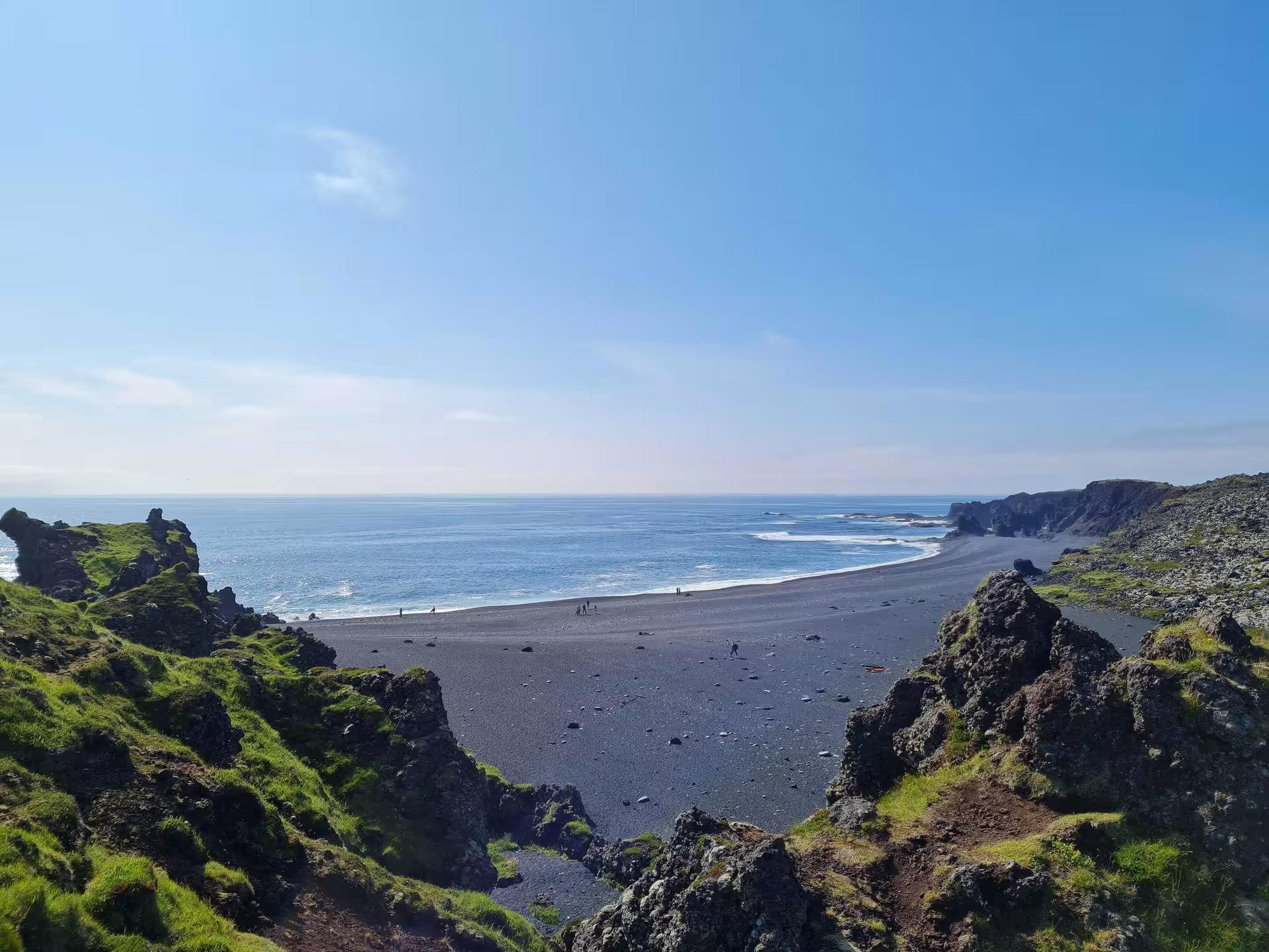 Black sand beach with volcanic rocks and green moss along Iceland's Ring Road coastline