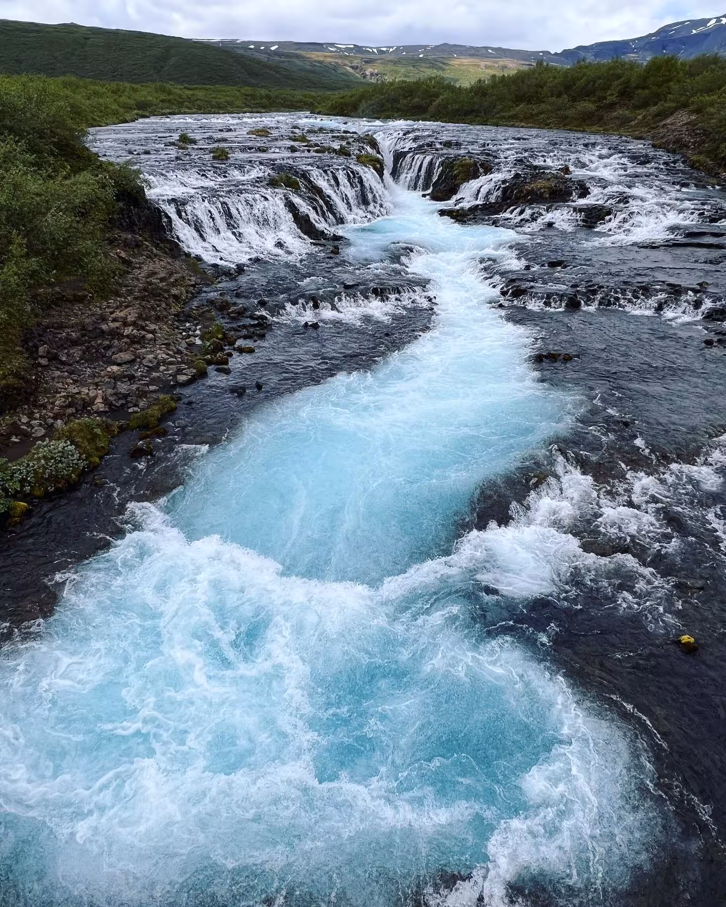 Vibrant blue waters of Bruarfoss waterfall surrounded by lush greenery on Iceland Ring Road tour.
