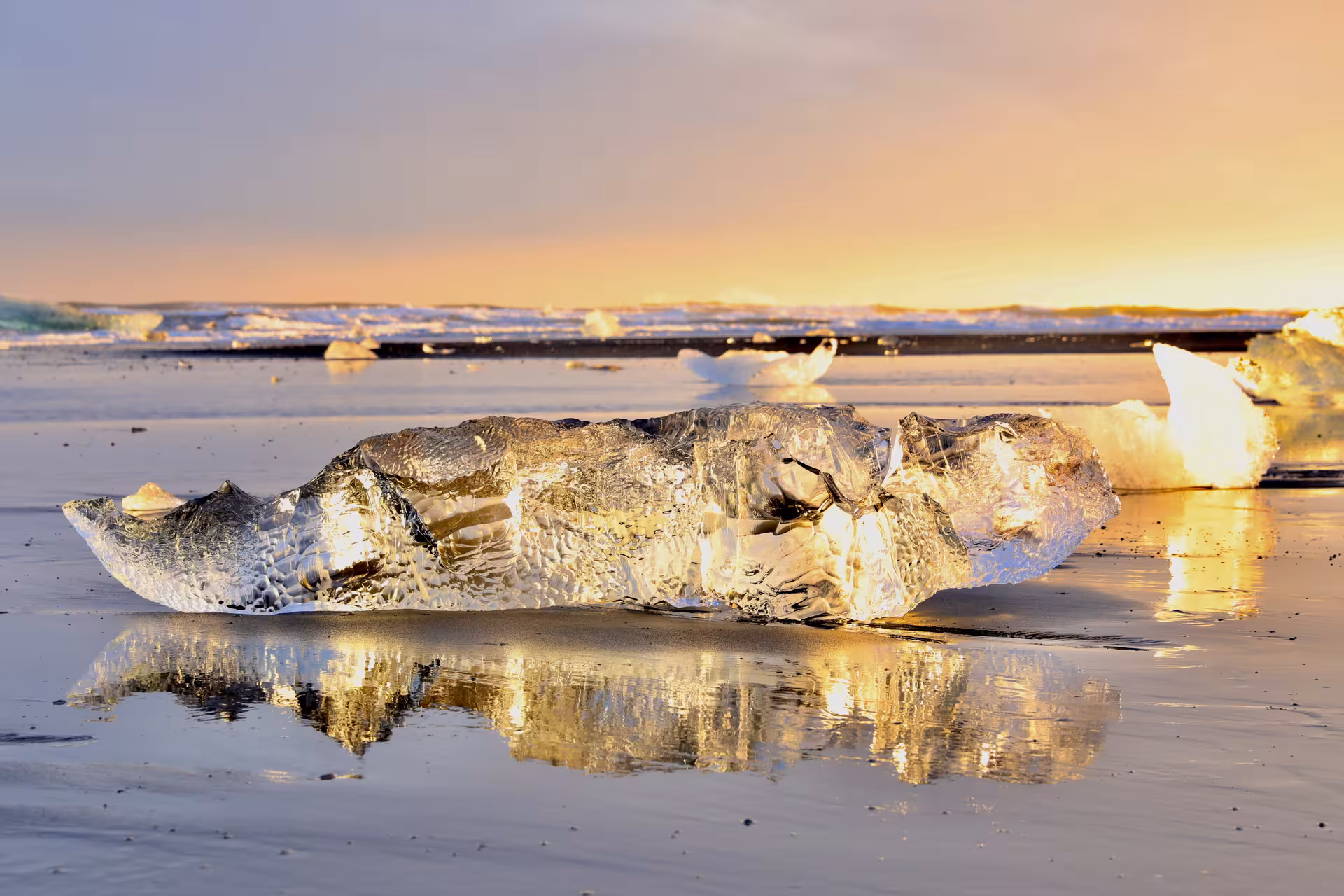 Glacial ice chunk glowing golden on Iceland's black sand Diamond Beach at sunset