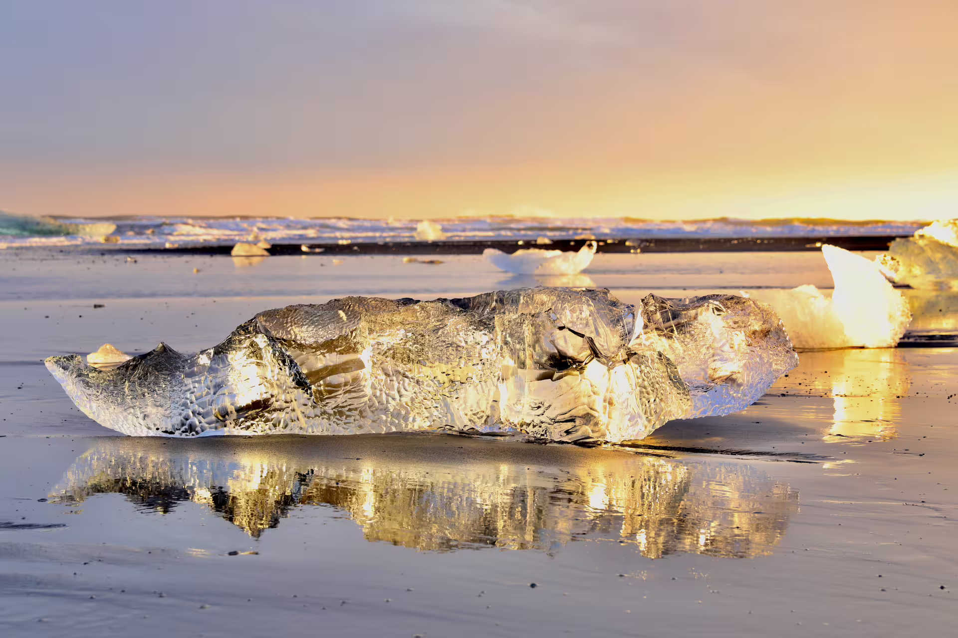 Glowing ice chunk on black sand beach at golden sunset, Diamond Beach Iceland