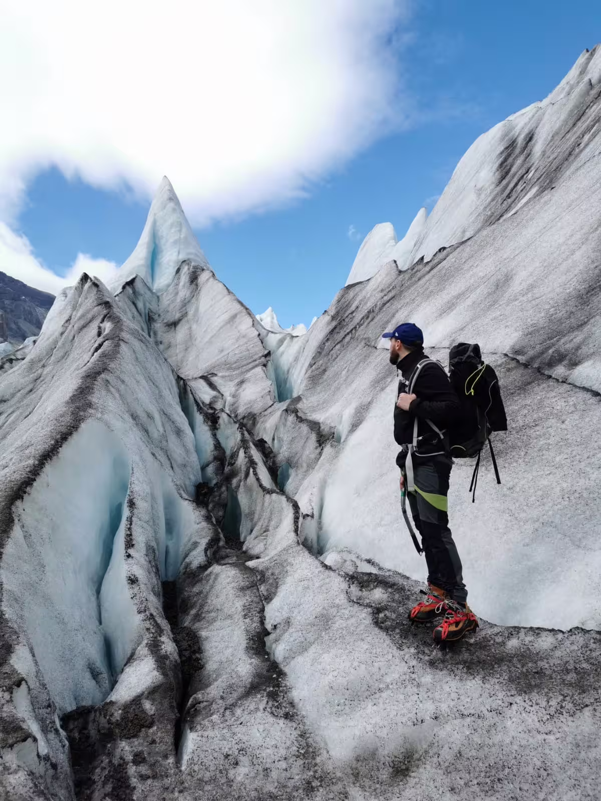 Hiker with backpack standing among dramatic glacier ice formations on Iceland Ring Road tour