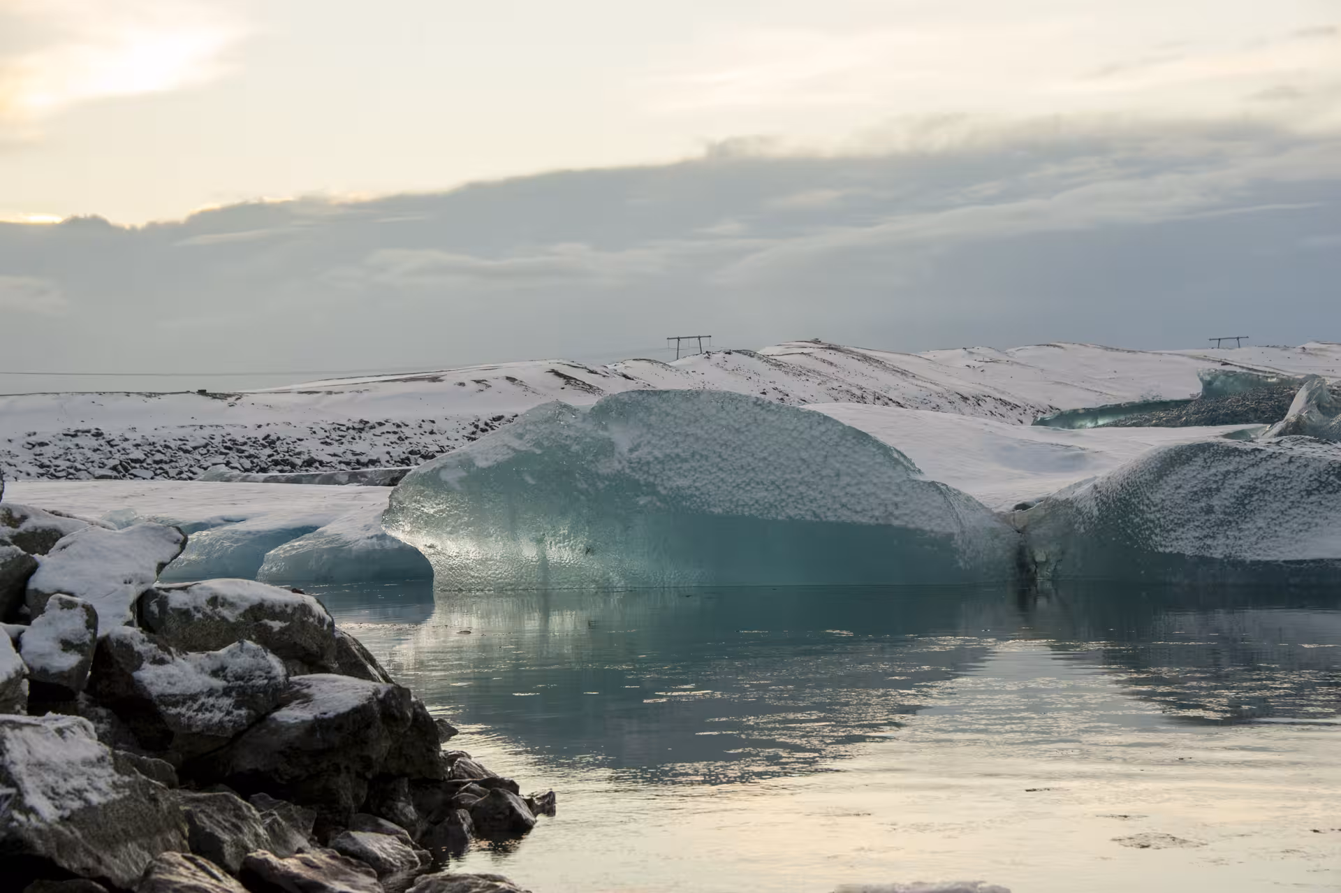 Turquoise icebergs floating in glacial lagoon with snow-covered landscape in Iceland