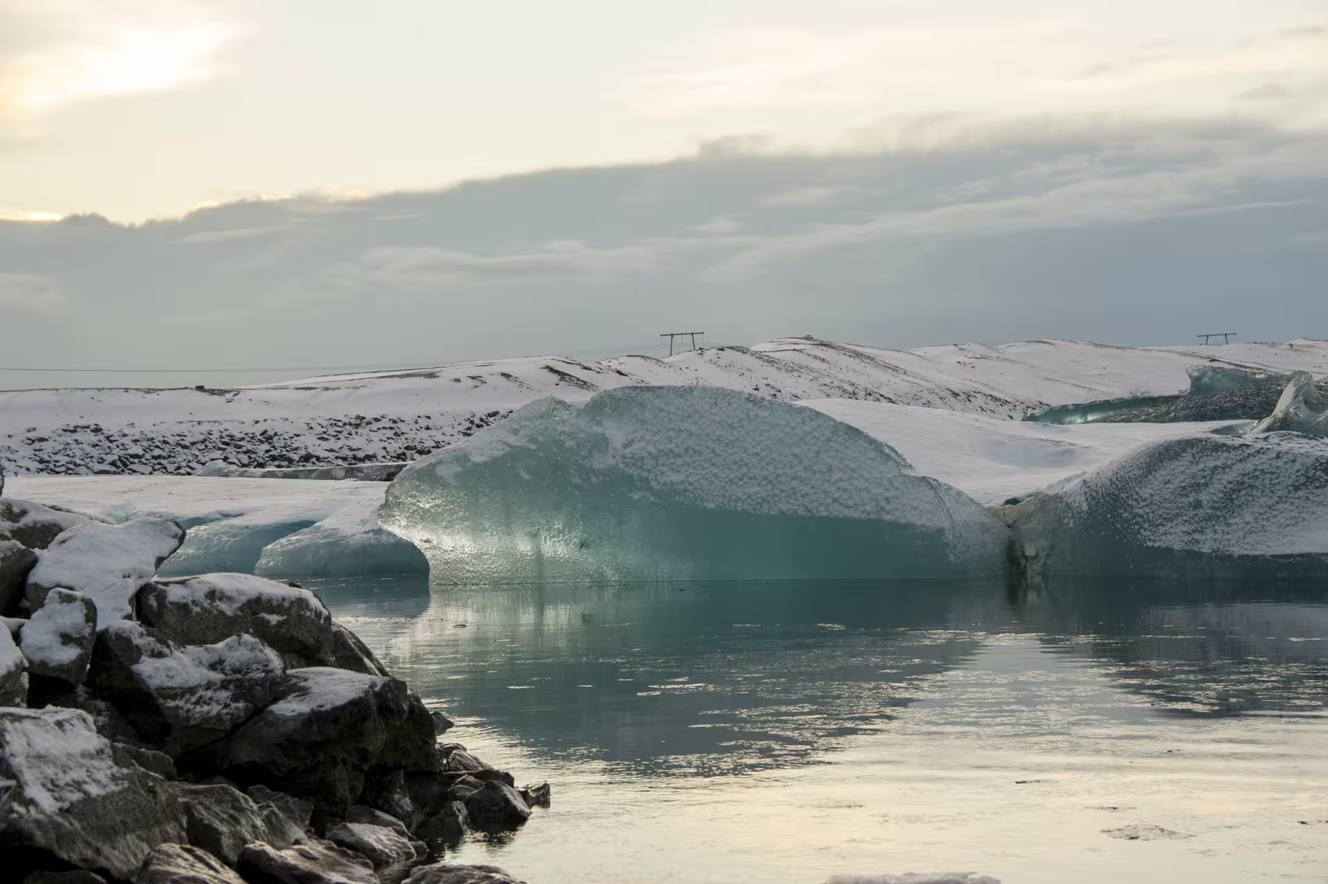 Turquoise icebergs floating in Jökulsárlón glacier lagoon with snow-covered hills in Iceland