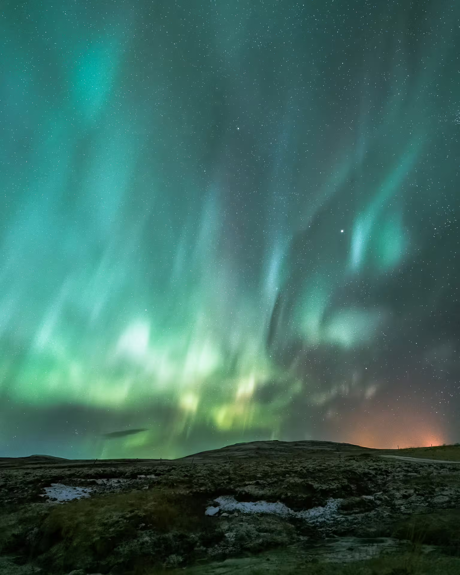 Vivid green aurora borealis dancing over dark volcanic landscape in Iceland at night