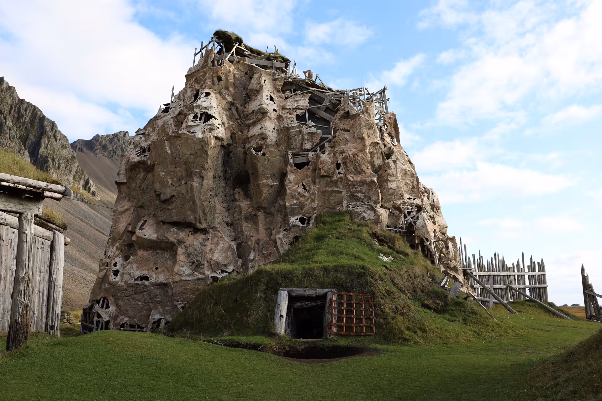 Ancient Viking village set with rocky outcrop, wooden structures, and tunnel entrance in Iceland