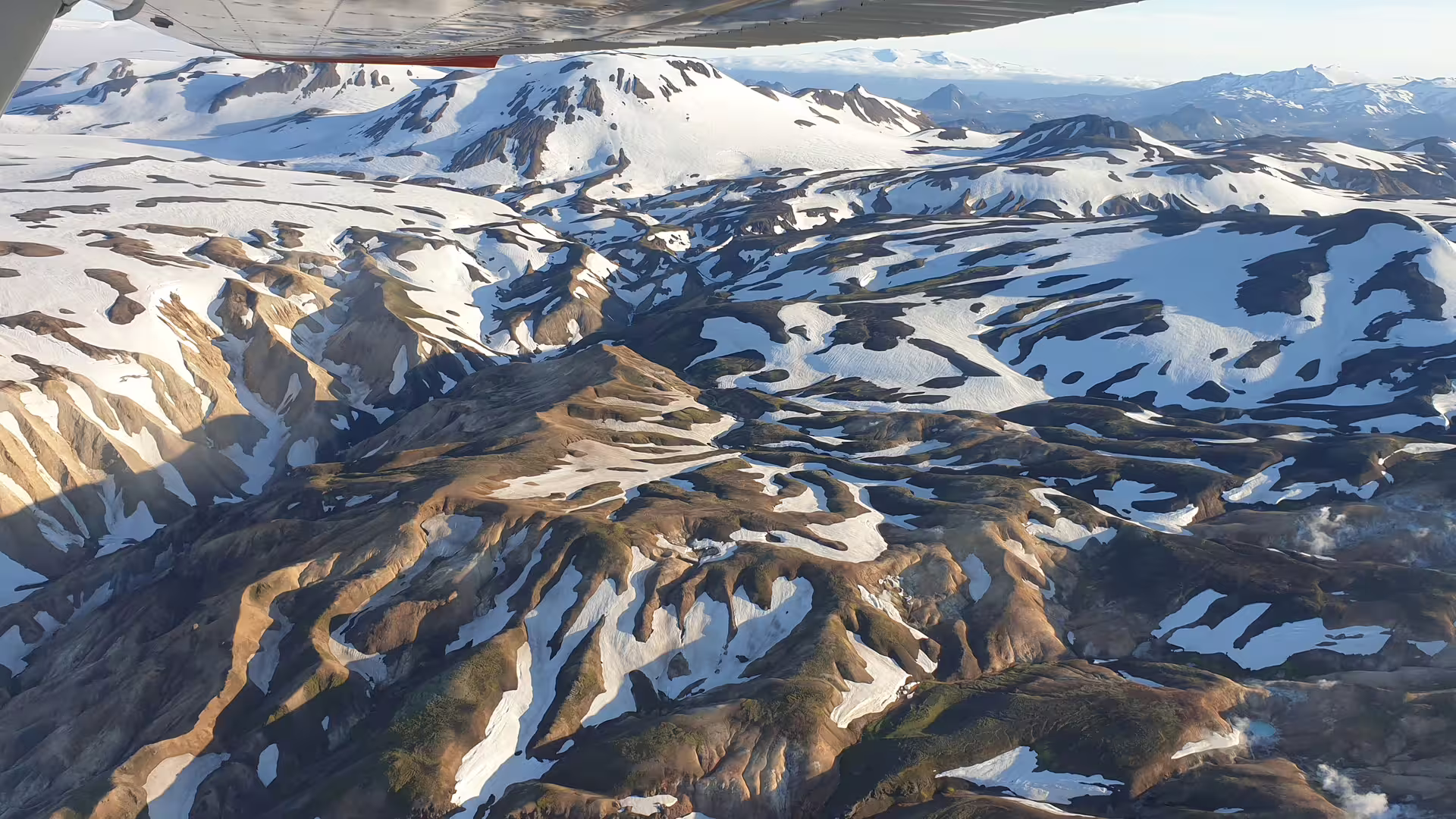Aerial view of snow-covered Icelandic highlands and glaciers seen from a small plane window