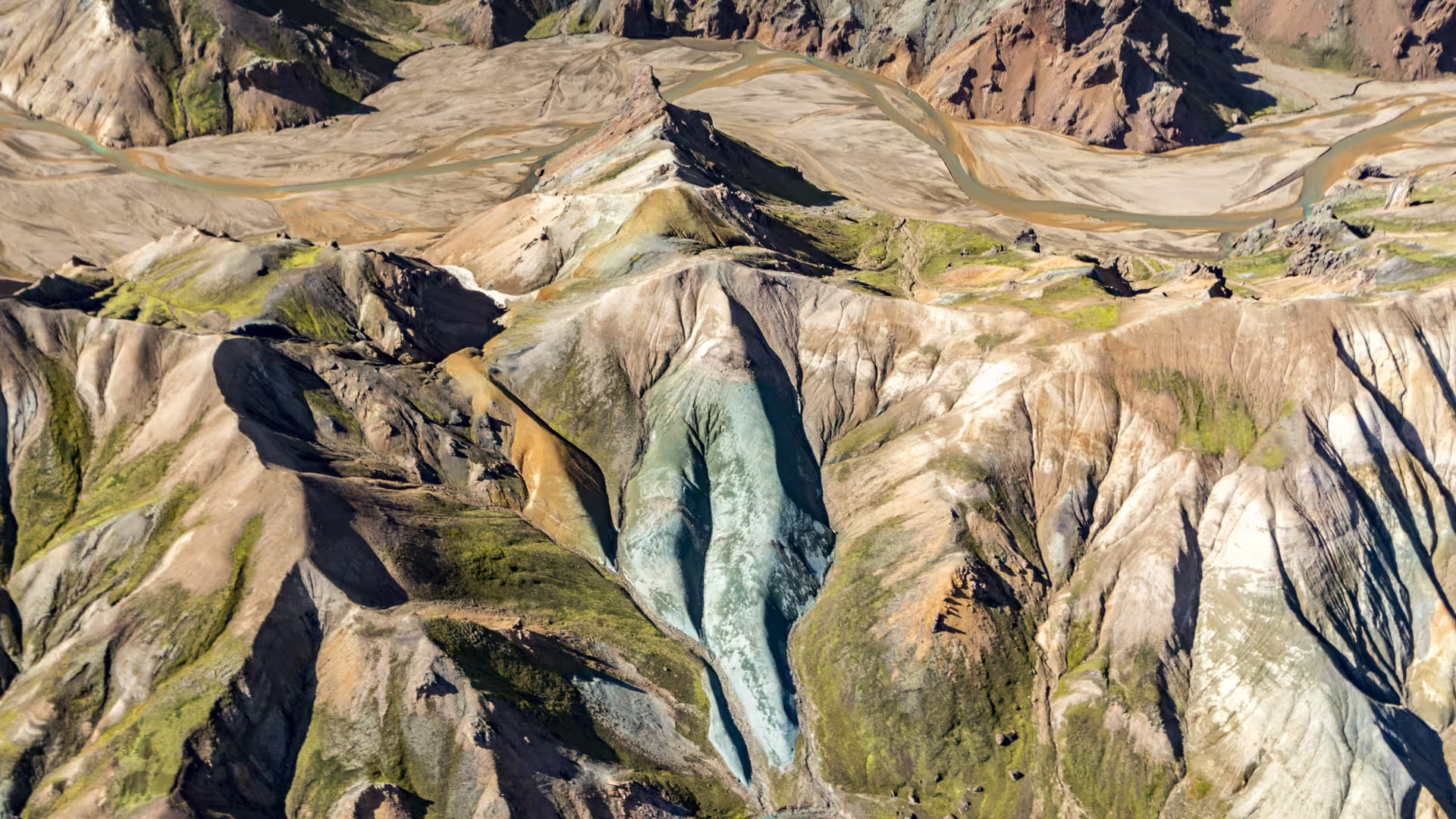 Aerial view of colorful volcanic mountains with glacial ice and braided rivers in Iceland's highlands