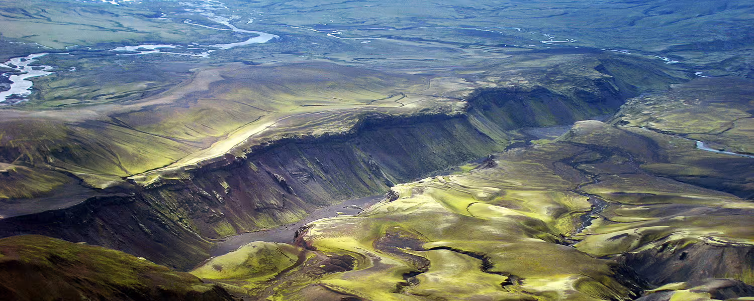 Aerial view of Iceland's green volcanic highlands with winding rivers and deep canyon from scenic flight